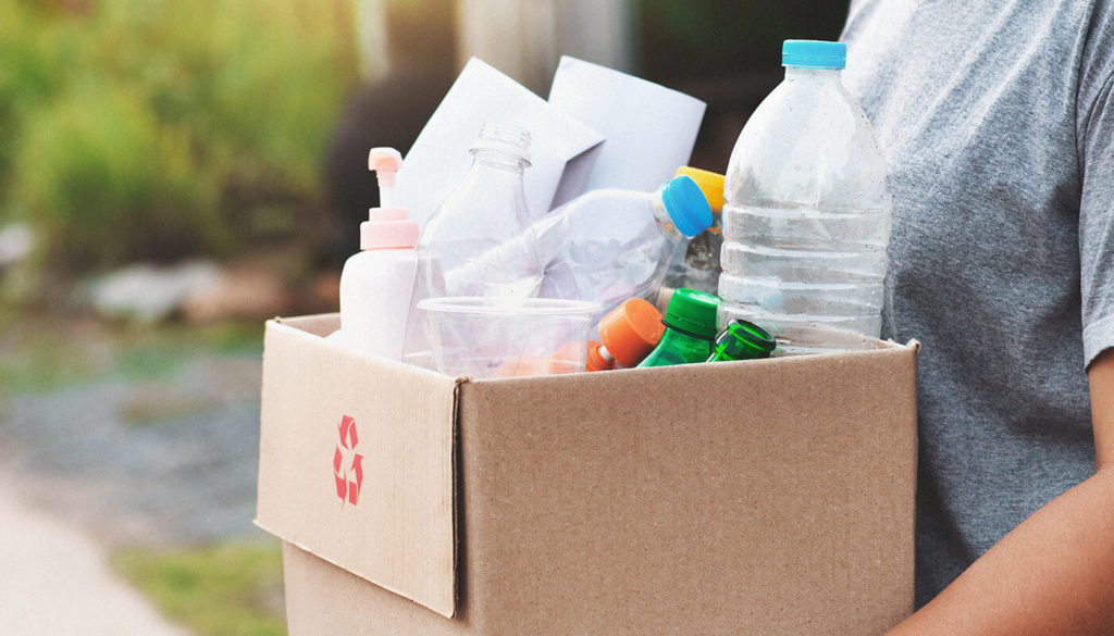 Person carrying a cardboard box of recyclable items