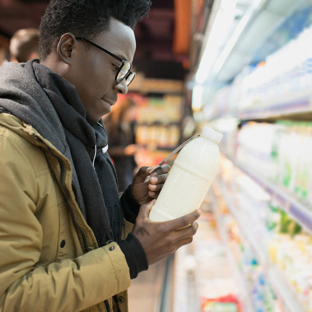 Person checking the food label on a pint of milk