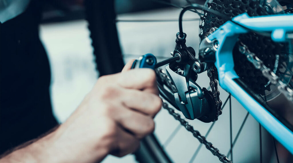 Man adjusting a bolt on a rear bicycle derailleur.